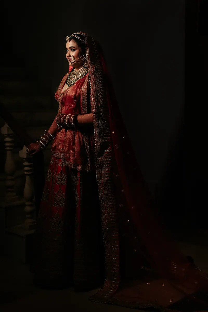 A bride in deep red, lit by a single window