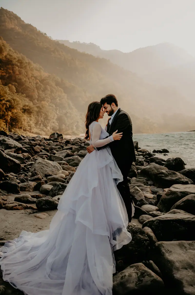 A couple embracing on a riverbed below the mountains
