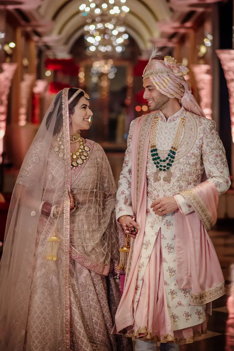 A couple in pastel ivory in a chandeliered hall