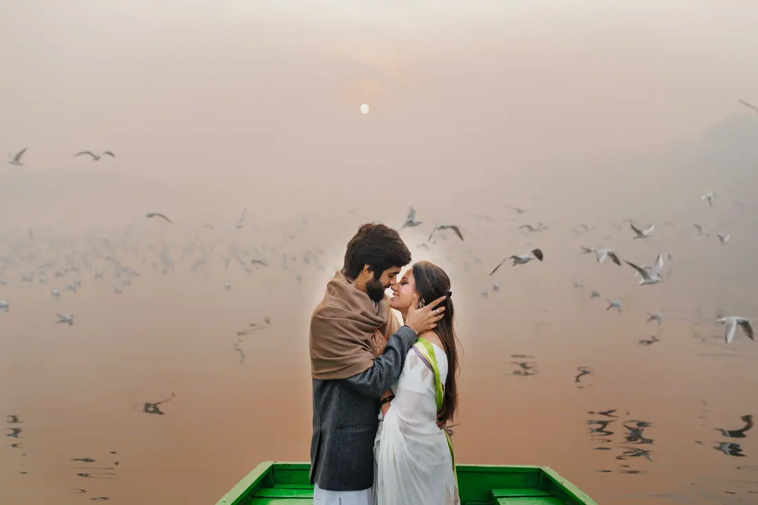 A couple on a boat as birds rise around them at dawn